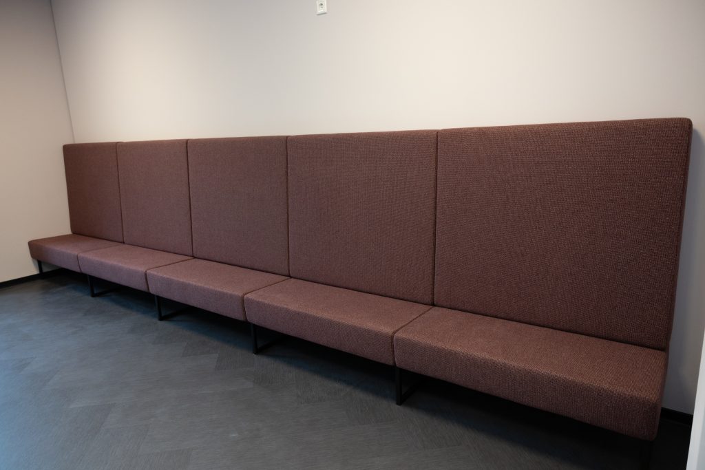 Lange Polsterbank im Empfangsbereich – fest montiert für wartende Besucherinnen und Besucher
