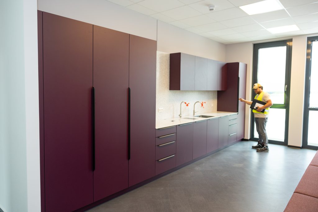 Monteur installiert Küchenschränke bei Nachrüstarbeiten im Innenraum